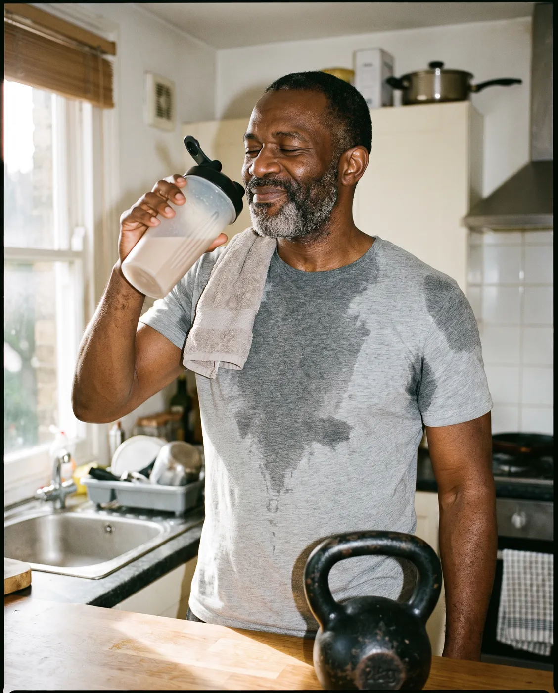 Man drinking a protein shake in his kitchen after a workout